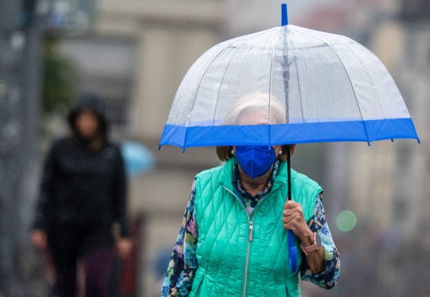 A woman holds a transparent umbrella to protect herself from the rain