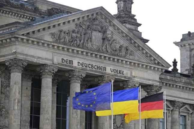 The EU, Ukrainian and German flags flutter in front of the Reichstag building housing the Bundestag (lower house of parliament) in Berlin