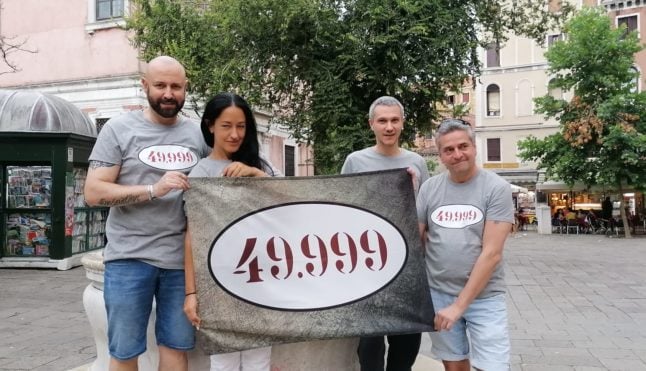 Activists hold up a banner displaying the number 49,999, as part of a campaign to draw attention to Venice's rapid depopulation. 