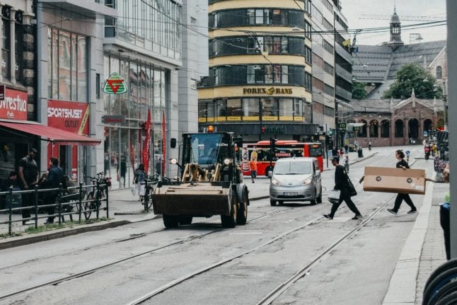 Pictured is a car and a tractor on Storgata in Oslo.