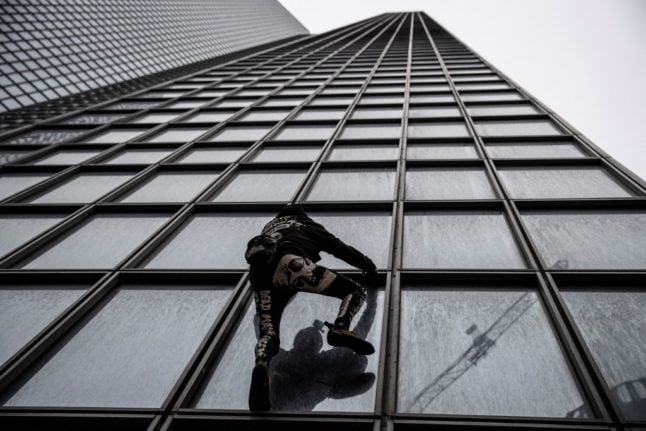 French solo free climber Alain Robert is pictured mid-climb as he scales the TotalEnergies tower in Paris' La Defense