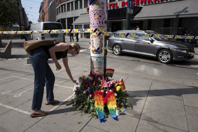 A mourner laying flowers at the site of a shooting.