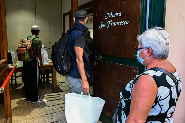 People come to collect a bag of food from Mario Conte's San Francesco soup kitchen, which is helped by the Catholic Caritas charity, on September 20, 2022 in Salerno.