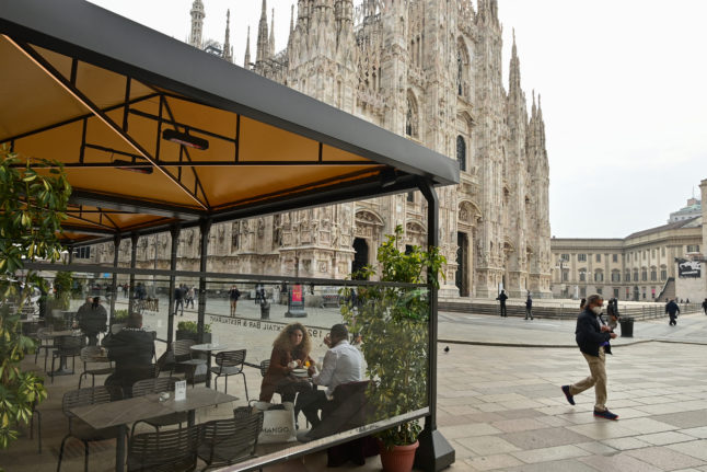 People enjoy an early autumn aperitivo next to Milan's duomo.