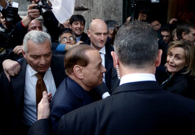 Silvio Berlusconi (C) surrounded by bodyguards, arrives at his home in downtown Rome on March 11, 2015.