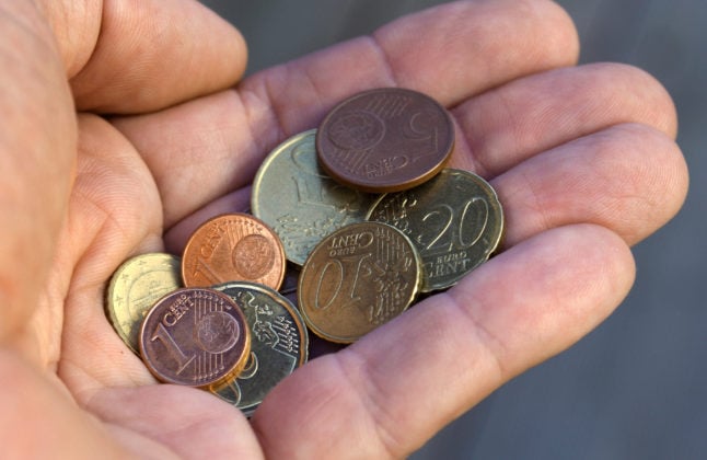 A hand holds various euro cent coins.