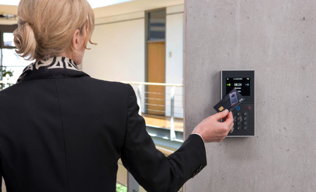 A woman demonstrates the method of recording working hours with a chip card.