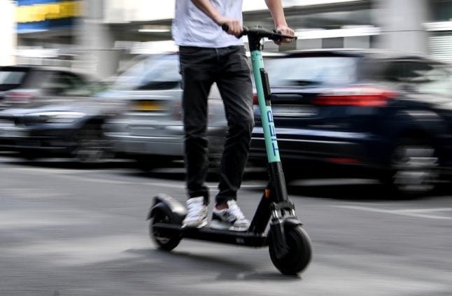 A man rides an e-scooter on a street in Berlin.