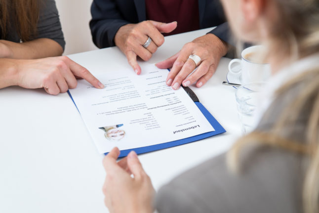 Two interviewers look at a candidate's CV during an interview.