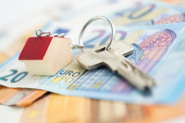 Euro notes lie next to some house keys on a table.