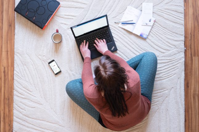 A woman works on the floor of her living room.