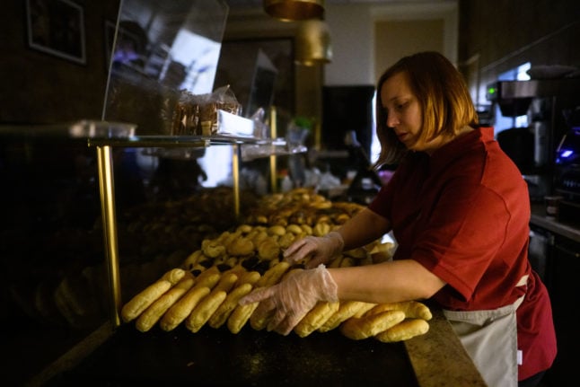 Bakery saleswoman Stefanie Buske stands in the early morning in the Fahrenhorst bakery, which is deliberately lit sparingly to save costs.