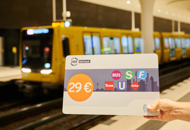 A person holds a sign to launch the start of sales of the €29 ticket in front of an arriving subway train in Berlin.