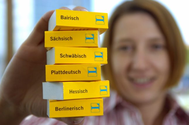 A woman holds mini German dialect dictionaries.