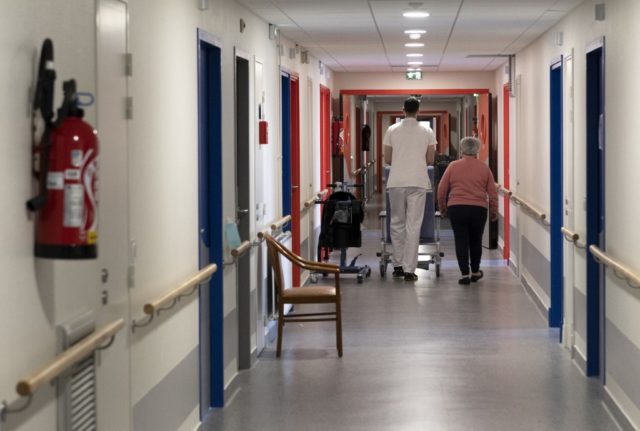 An elderly care home resident walks with an employee.