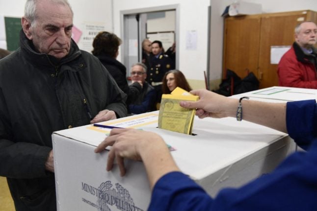 A citizen watches a polling station officer casting his ballot on March 4, 2018 at a poll in Milan, Italy.