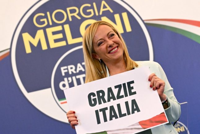 Leader of Italian far-right party "Fratelli d'Italia" (Brothers of Italy), Giorgia Meloni holds a placard reading "Thank You Italy" after she delivered an address at her party's campaign headquarters overnight on September 26, 2022 in Rome.