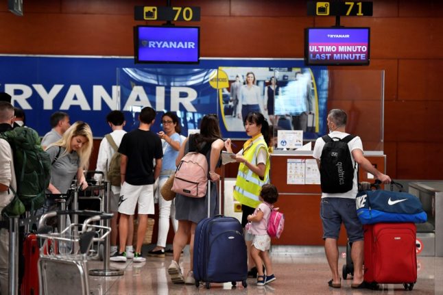 A Ryanair employee talks to a passenger at the check-in counters at the Terminal 2 of El Prat airport in Barcelona on July 1, 2022.