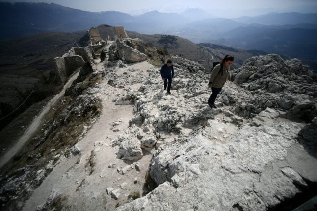 People walk by the castle of Rocca Calascio in Abruzzo's national park on March 29, 2022. 