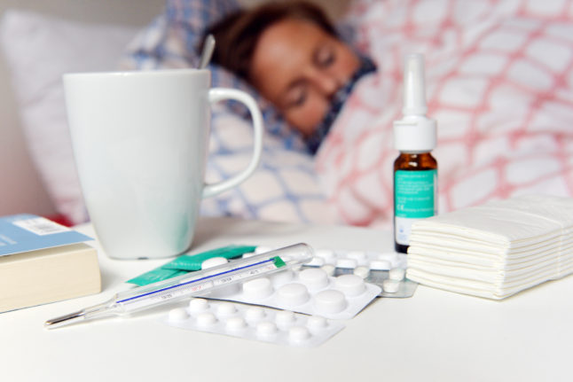 Medicines and a fever thermometer lie on a bedside table.