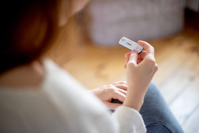 A woman holds a positive antigen test for Covid-19.