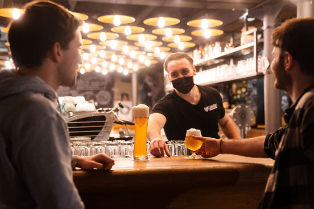 A bartender serves drinks to two customers