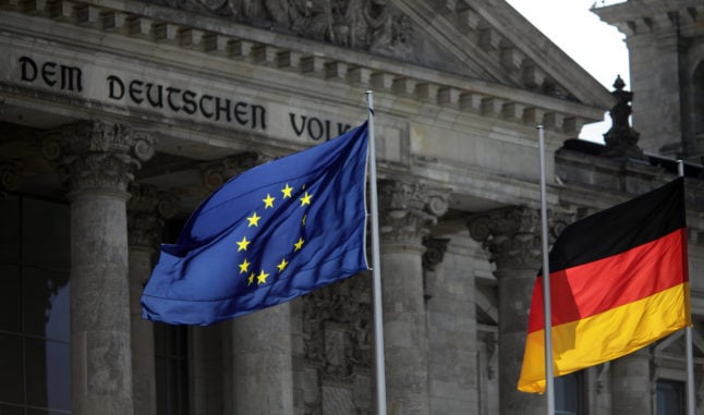 The European and German flags wave in the wind in front of the Reichstag in Berlin.