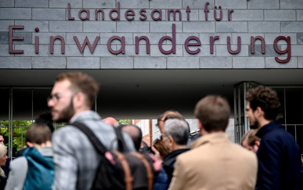 People stand in front of the Berlin State Office for Immigration.