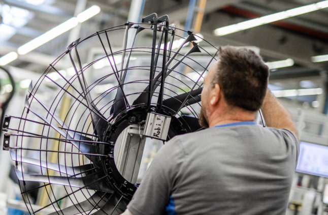 An employee of an electric motor and fan manufacturer, works on a fan in production.