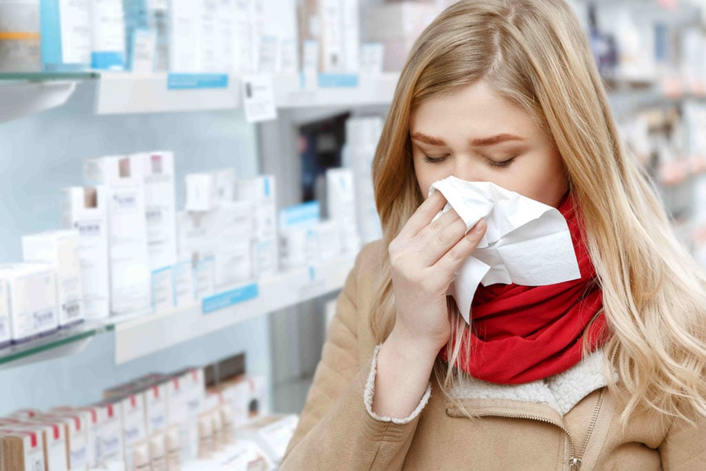 A woman with a cold visits a pharmacy.