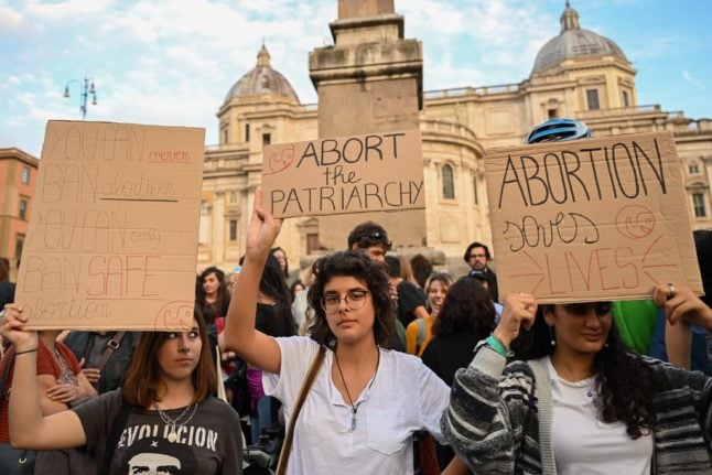 People hold placards as they take part in gathering to mark the annual International Safe Abortion Day, on September 28, 2022 in downtown Rome.