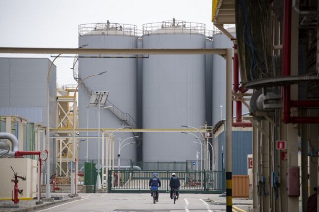 Two workers ride bicycles at the Barcelona's Enagas regasification plant.