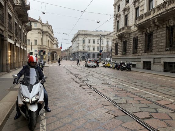 A man parks his scooter by the Teatro alla Scala in downtown Milan