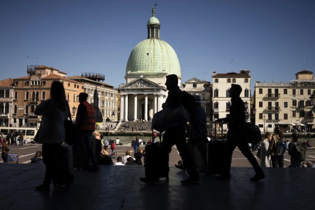 Tourists leave the Santa Lucia train station on the Grand Canal in Venice, on May 16, 2019.