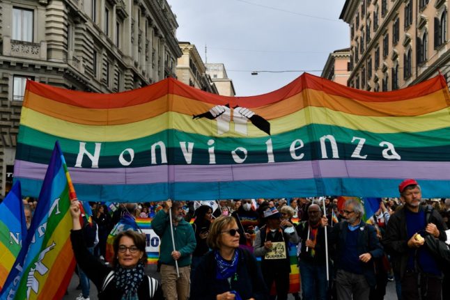 People march with a rainbow flag that says 'no violence' in Rome