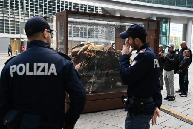 Police watch an exhibit containing the remains of  the escort car of Italian judge Giovanni Falcone, who was assassinated by the mafia in 1992.