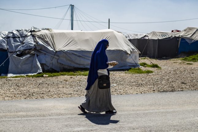 A woman walks through Syria's Camp Roj