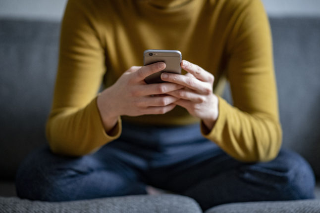 A young woman holds a smartphone in her hand.