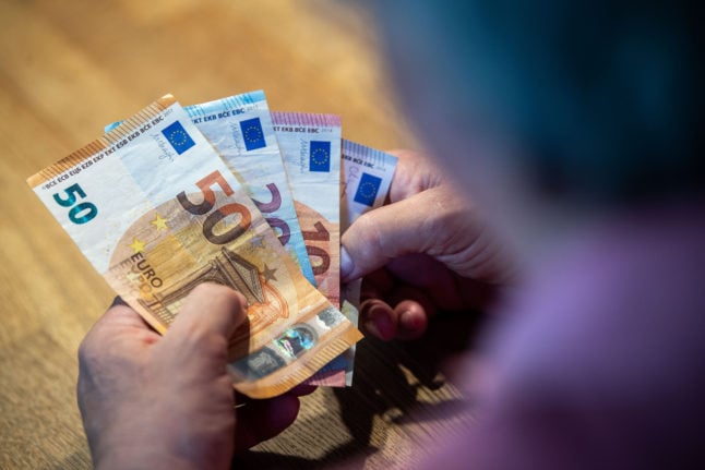A person in Germany holds cash. The government has pledged to clamp down on gas prices.