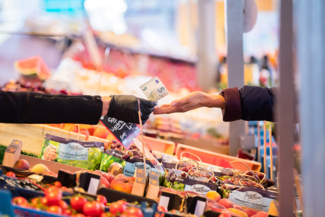 Money is handed over a fruit and vegetable counter at a weekly market in the Schöneberg district of Berlin.