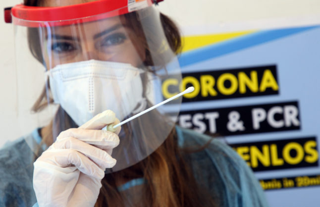 An employee in a Covid testing center poses with a test stick for Covid rapid testing.