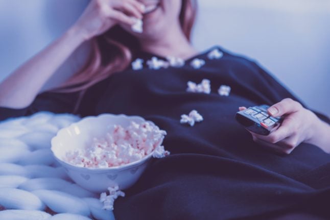 Woman eating popcorn with a TV remote