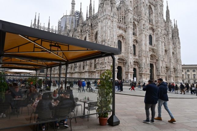 People enjoy a drink at a cafe terrace on Duomo square in downtown Milan on February 6, 2021, as the Italian government eased anti-Covid restrictions in the Lombardy region, during the Covid-19 pandemic.