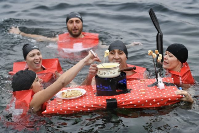 people eat a cheese fondue as they swim in the Lake Geneva Christmas Cup race