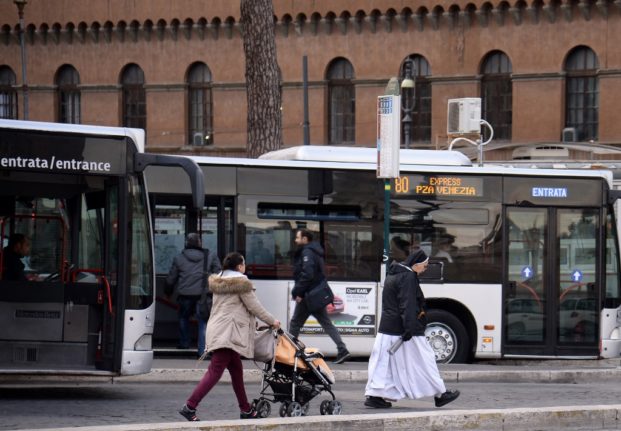 A nun walks past a bus at a public transport station on January 31, 2017 at Piazza Venezia in Rome. Public transport system (Atac) has a bad reputation in Rome where users are complaigning about delays and frequency of the buses.