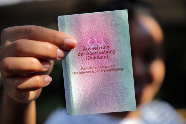 A migrant in Germany holds up their 'Duldung' notice