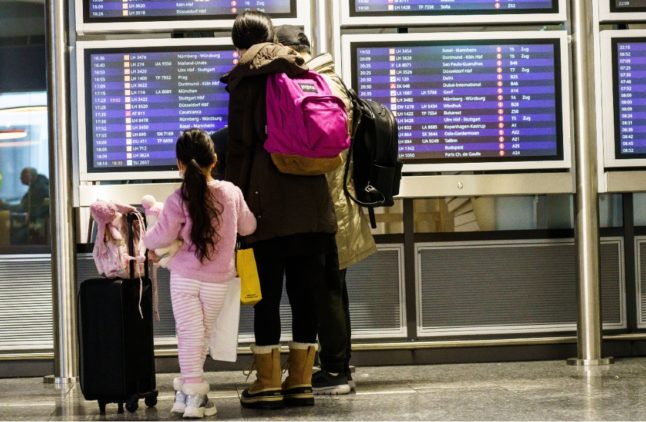 Passengers check the departures board at Frankfurt airport.