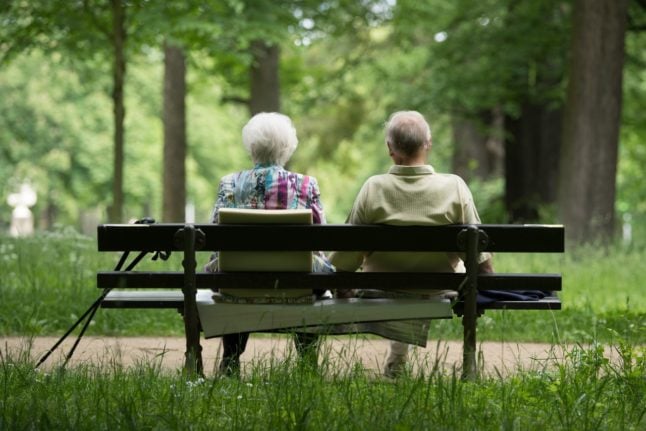 Two retirees sit on a park bench in Dresden