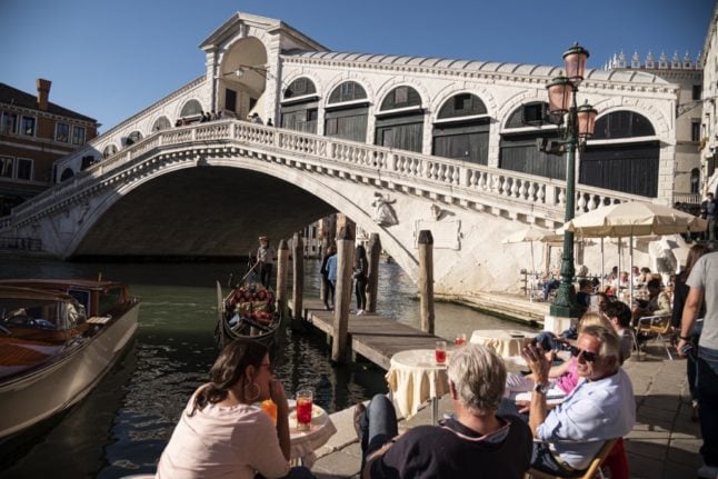 Tourist sitting in a cafè by Rialto Bridge in Venice