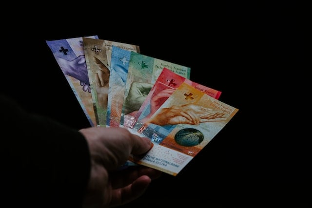 A person holding a handful of Swiss francs